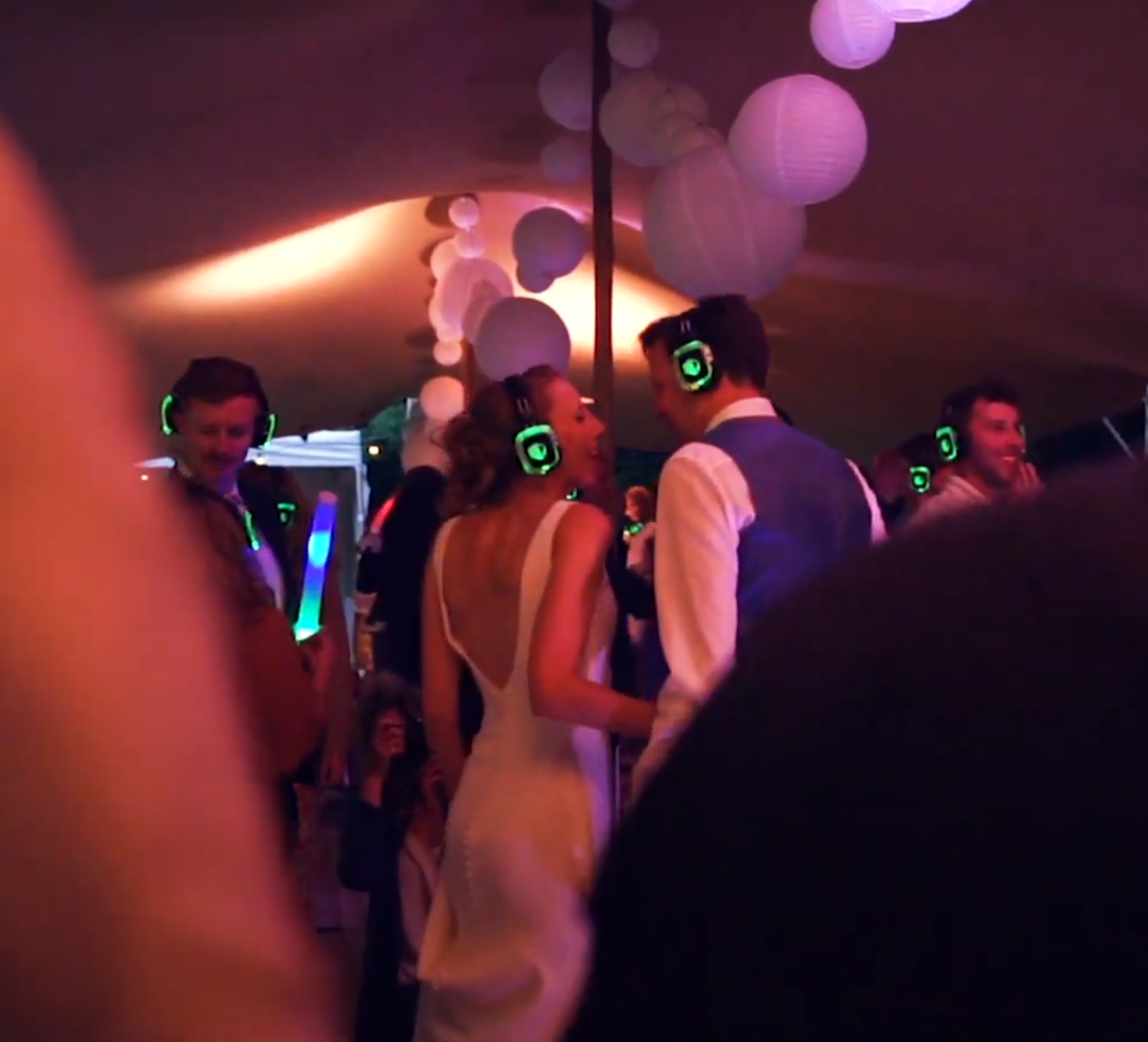 mensen op een feest met koptelefoons op met een dj op de achtergrond
